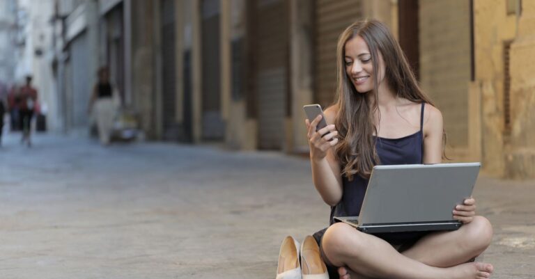 Personne souriante creant une adresse courriel sur un telephone et un ordinateur portable