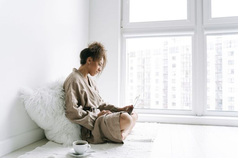 woman reading on laptop by window