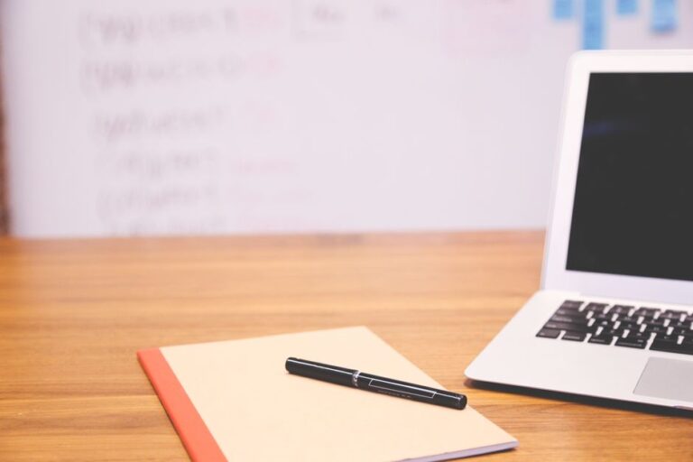 laptop with notebook and pen on desk