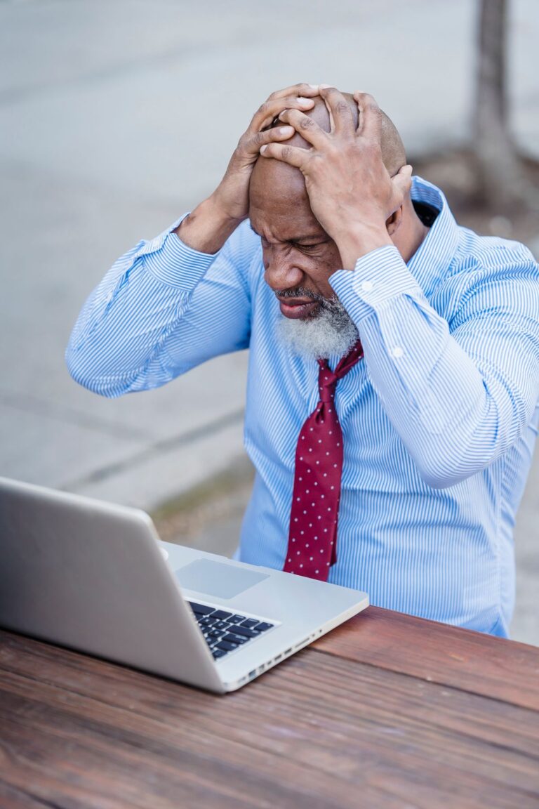Homme inquiet se tenant la tête devant son ordinateur, compte piraté