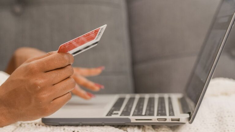 Personne tenant une carte de crédit pour magasiner en ligne
