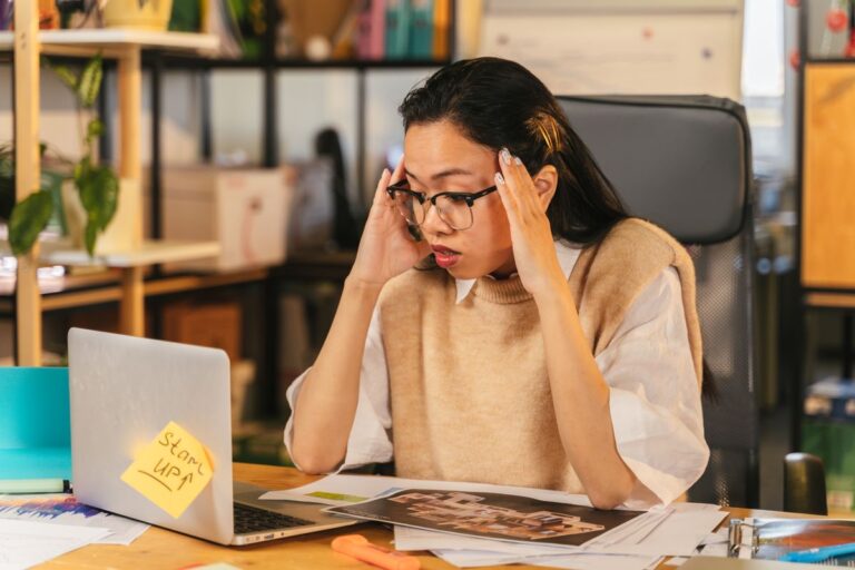 Femme portant des lunettes montrant du stress devant un ordinateur portable