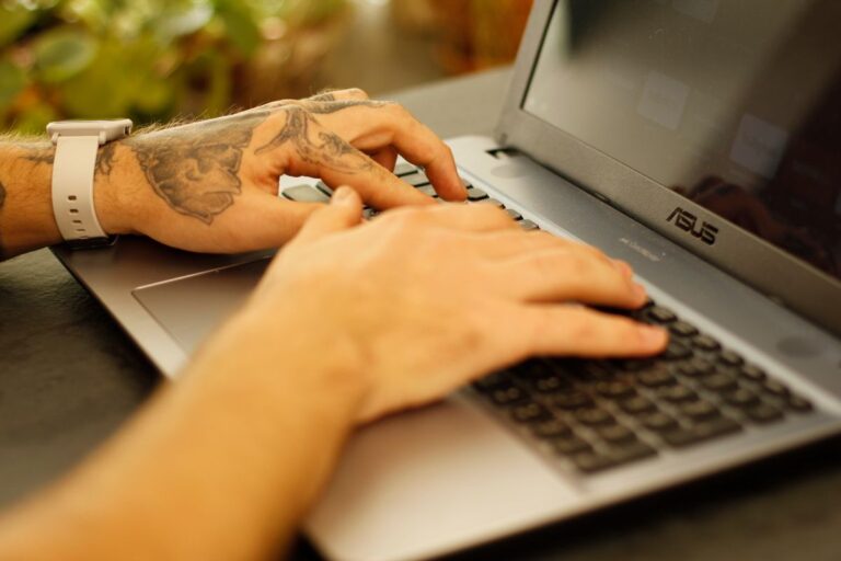 Mains tatouées tapant sur un ordinateur portable, concentrées