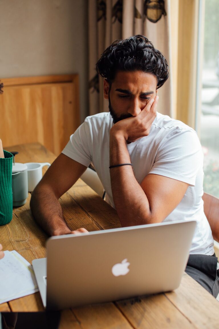 Homme réfléchissant devant son ordinateur portable