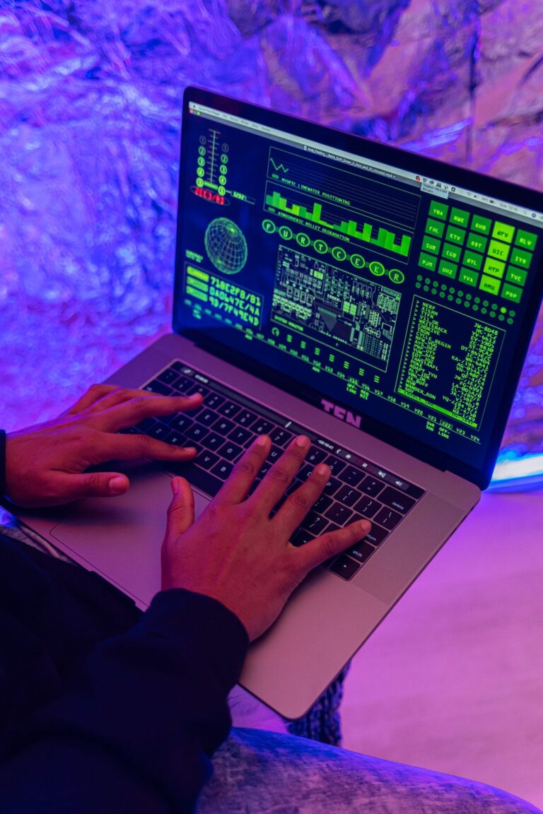 Mains tapant sur un ordinateur portable affichant du code, éclairage violet