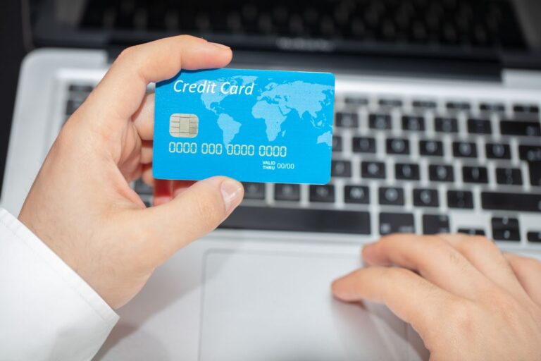 Personne tenant une carte de crédit près d'un ordinateur portable