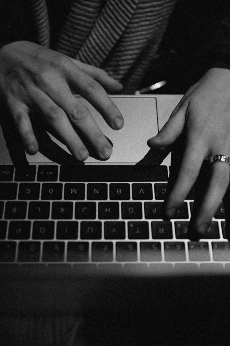 Image monochrome de mains tapant sur un ordinateur portable